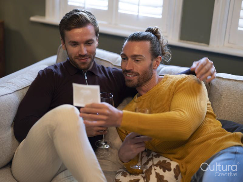 couple looking at ultrasound scan while relaxing on sofa