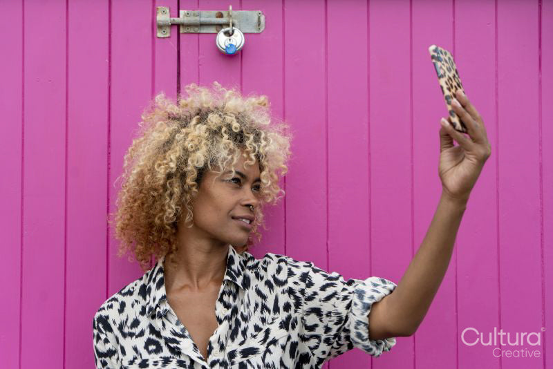 Woman taking selfie against pink wall