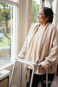 Senior woman using mobility walker and looking through window in nursing home