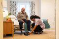 Nurse helping senior man to get dressed at nursing home