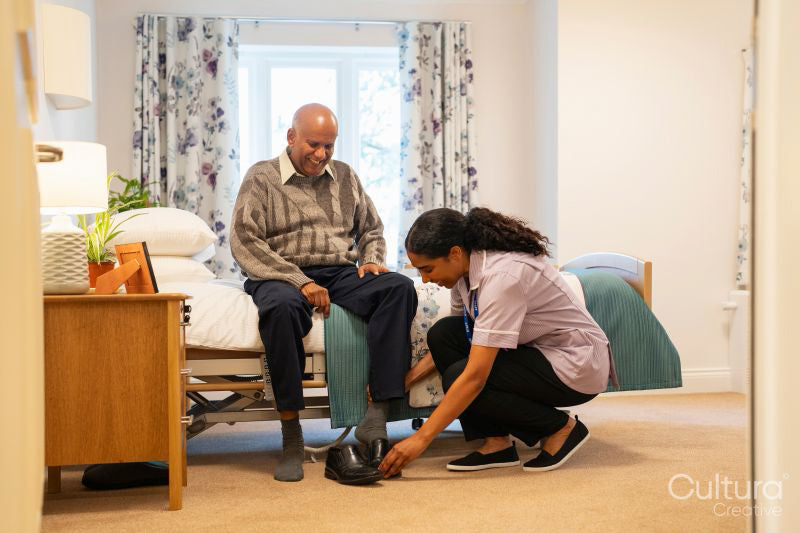 Nurse helping senior man to get dressed at nursing home