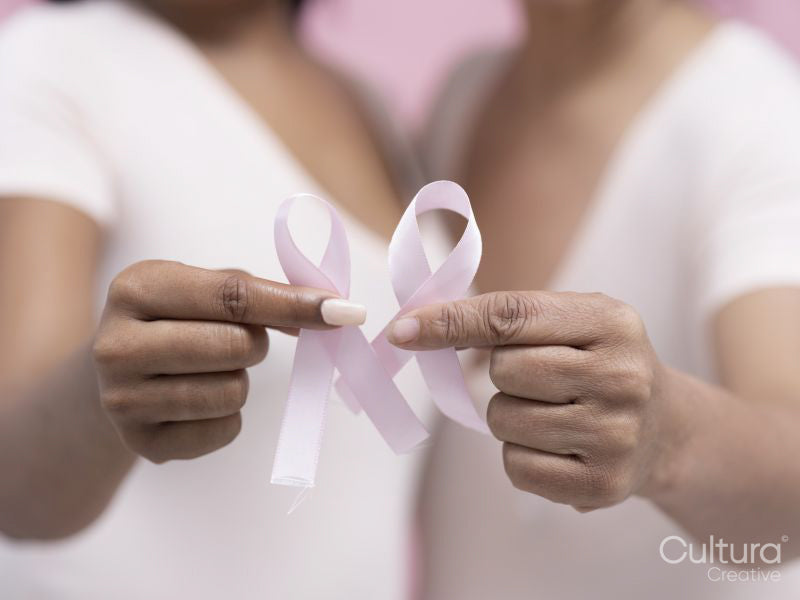 Close-up of women's hands holding pink breast cancer awareness ribbon