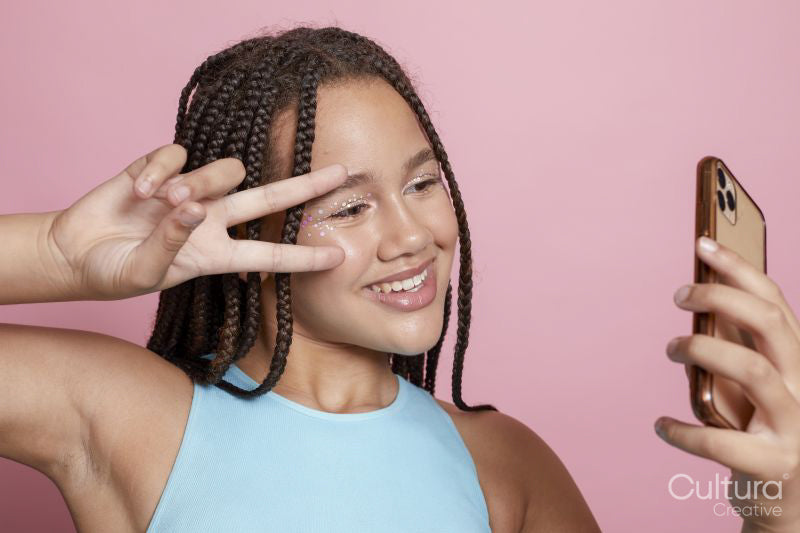Studio shot of smiling girl with braids taking selfie