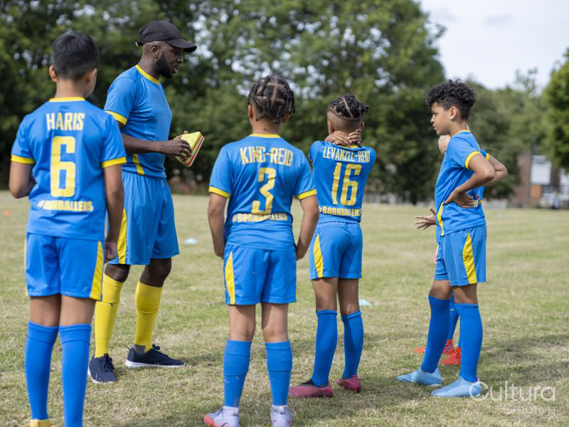 Coach meeting with kids on soccer field