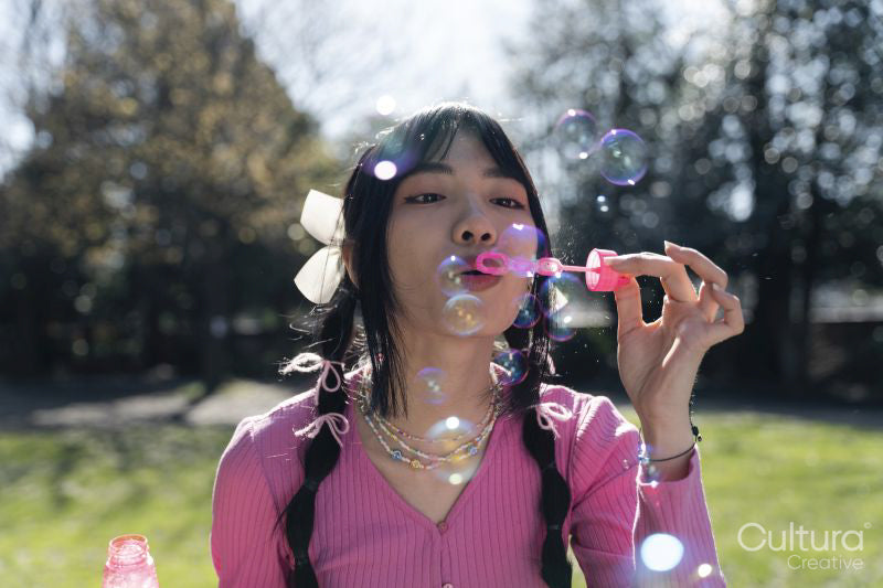 Young woman blowing bubbles in park
