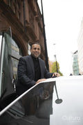 Mature man leaning against luxury car