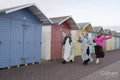 Cheerful Muslim friends waving while walking next to beach huts