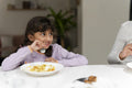 Little girl eating meal at table