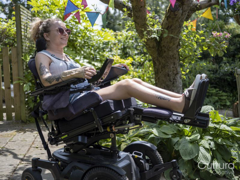 Woman in electric wheelchair sunbathing in back yard