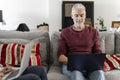 Smiling mature man working on laptop on sofa at home