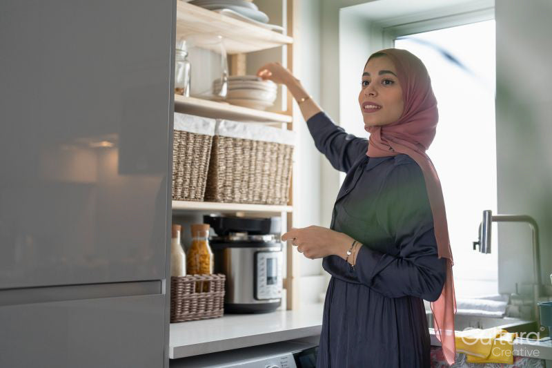 Woman in hijab putting dishes on shelf