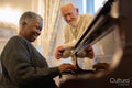 Smiling senior man looking at senior woman playing piano