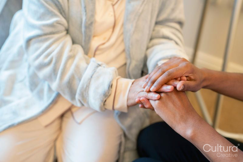 Nurse holding hands of senior lady at nursing home