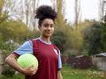 Portrait of female soccer player with ball outdoors
