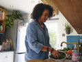 Woman washing vegetables in kitchen sink