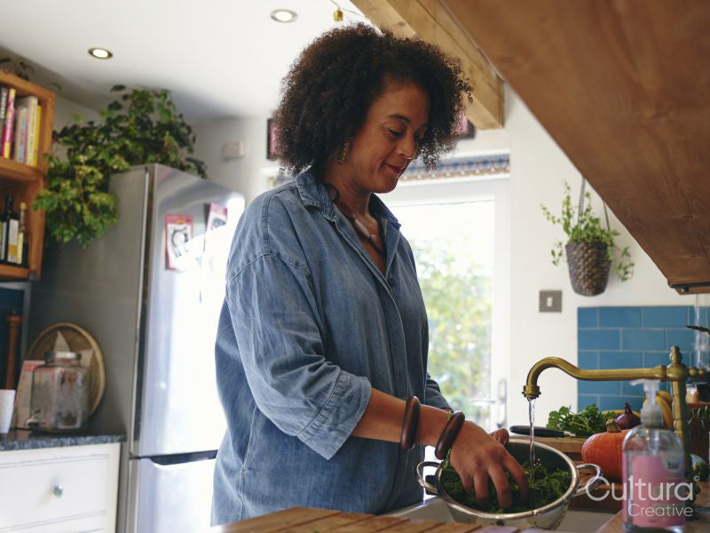Woman washing vegetables in kitchen sink