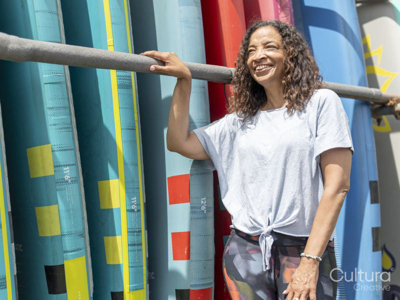 Portrait of smiling woman standing next to paddleboard rack