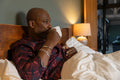 Man drinking coffee while lying in bed in morning