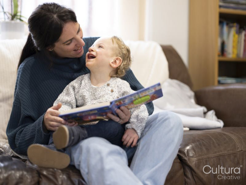 Happy boy reading with mother on sofa