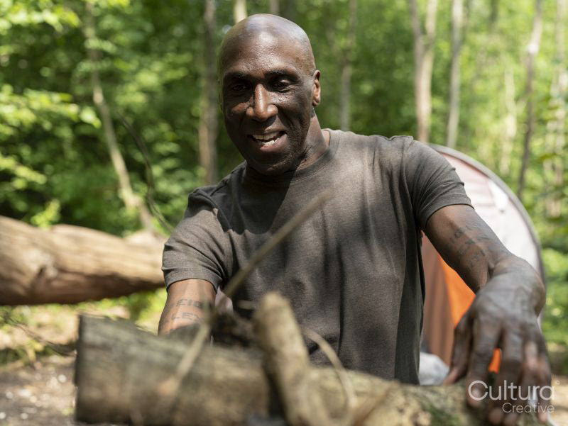 Mature man making fire in forest