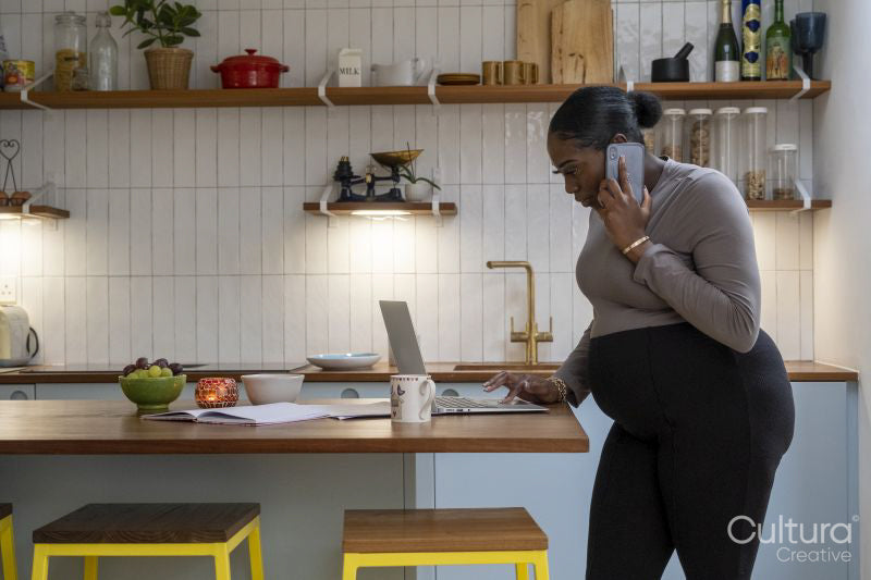 Pregnant woman talking on mobile phone in kitchen