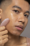Close-up of person using rose quartz guasha
