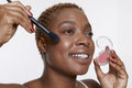 Studio portrait of smiling woman applying blush