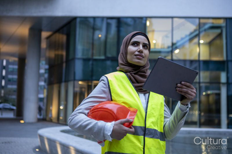 Female engineer in hijab holding tablet on front of modern building