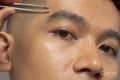 Close-up of person tweezing eyebrow