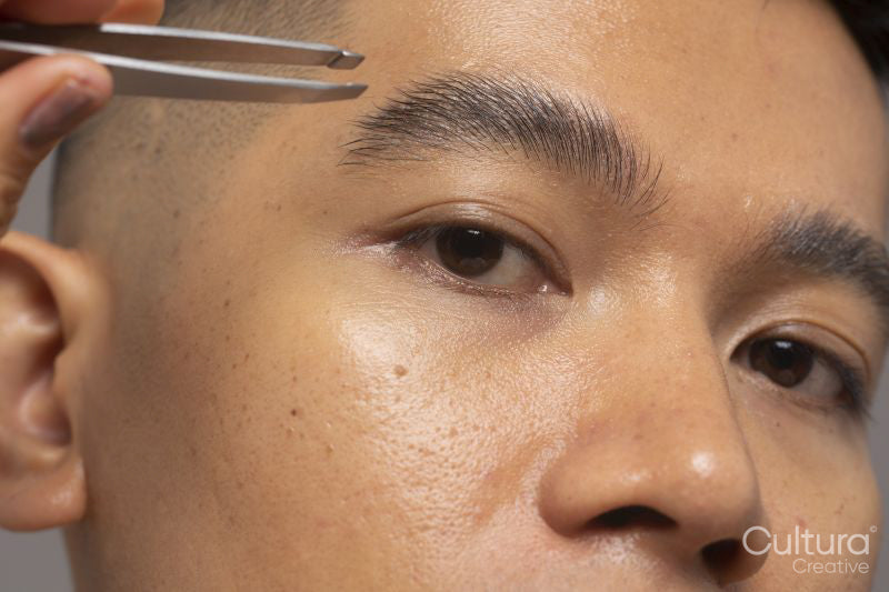 Close-up of person tweezing eyebrow