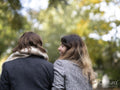 Back view of female couple walking in park at autumn