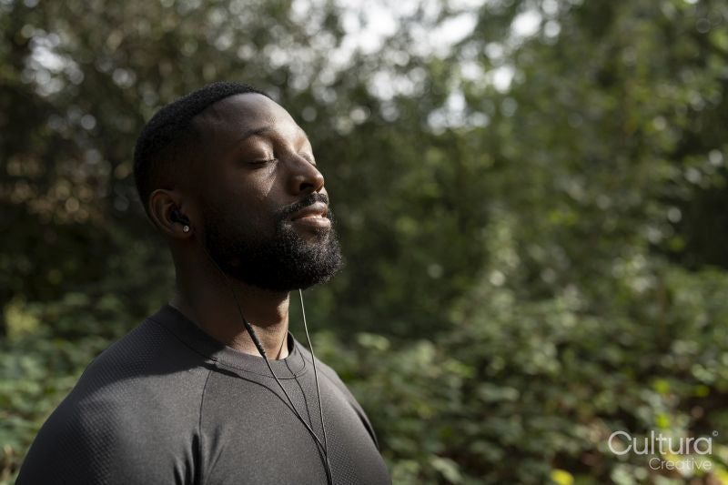 Portrait of athletic man with earbuds standing in park