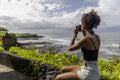 Indonesia, Bali, Female tourist photographing sea from observation point