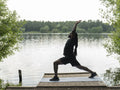 Man practicing yoga by lake