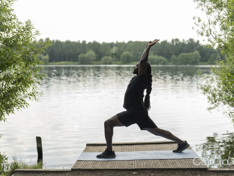 Man practicing yoga by lake