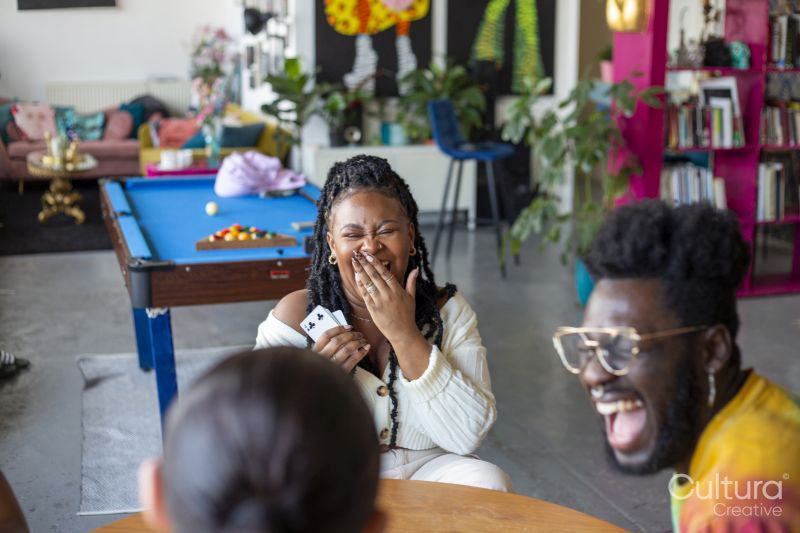 Friends laughing while playing cards at home