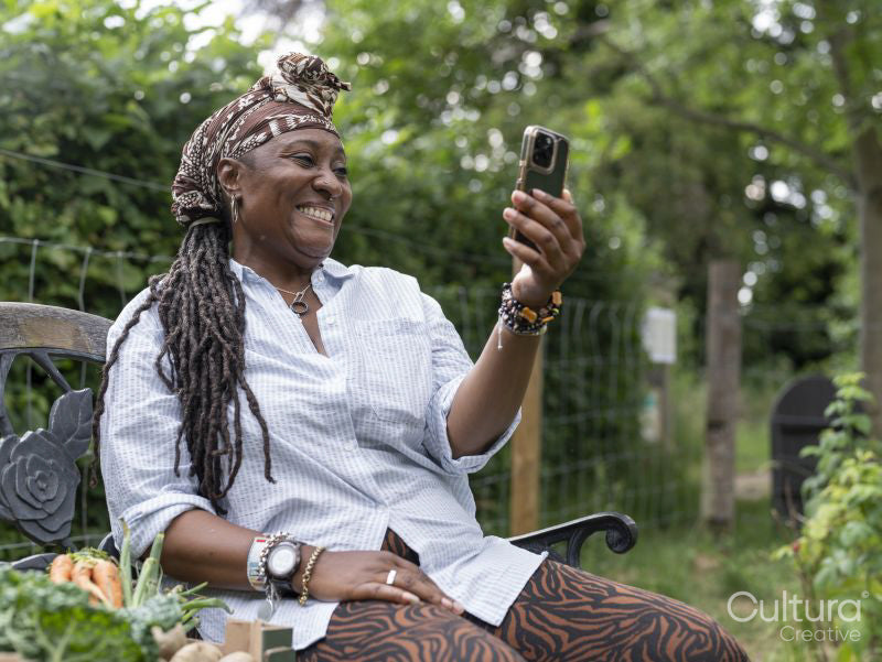Smiling woman using phone after working in garden