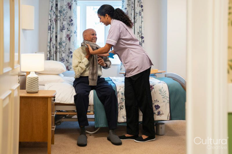 Nurse helping senior man to get dressed at nursing home