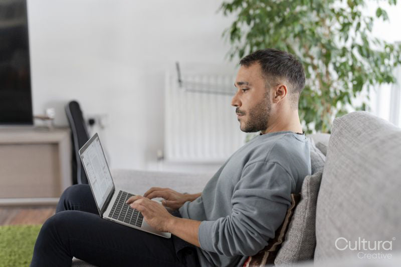 Mature man working on laptop on sofa at home