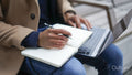 Mid section of business man holding laptop and notepad