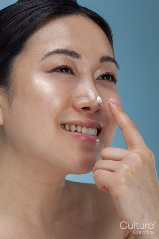 Close-up of smiling woman applying face cream