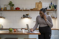 Pregnant woman talking on mobile phone in kitchen