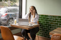 Smiling woman with laptop and smart phone at cafe table