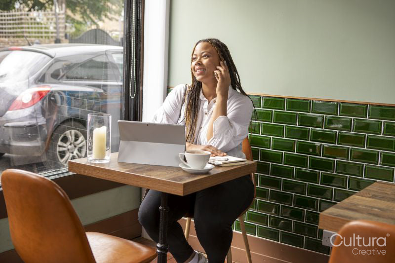 Smiling woman with laptop and smart phone at cafe table
