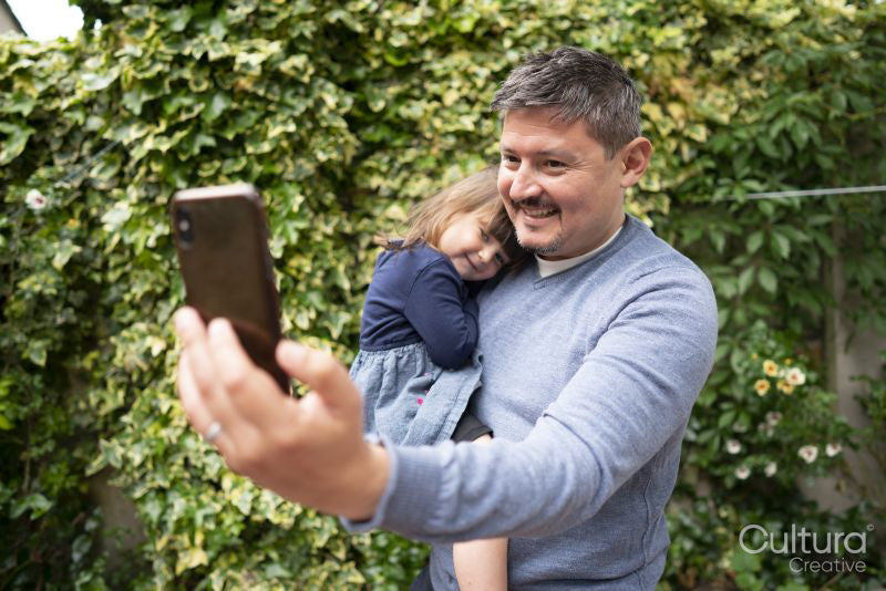 Smiling man taking selfie with daughter outdoors
