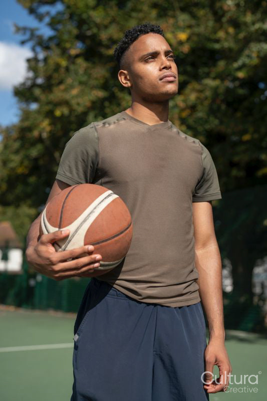 Portrait of pensive man with basketball ball in basketball court