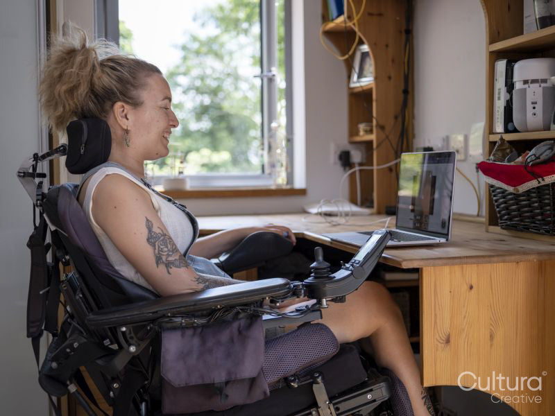 Woman in electric wheelchair working on laptop