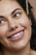 Close-up of young woman applying face serum