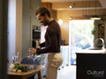 Young man pouring wine at home kitchen