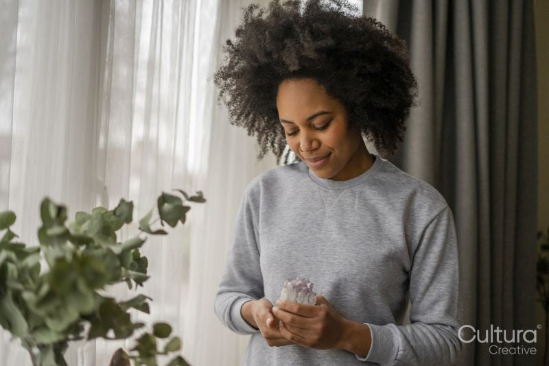 Smiling young woman holding crystal at home